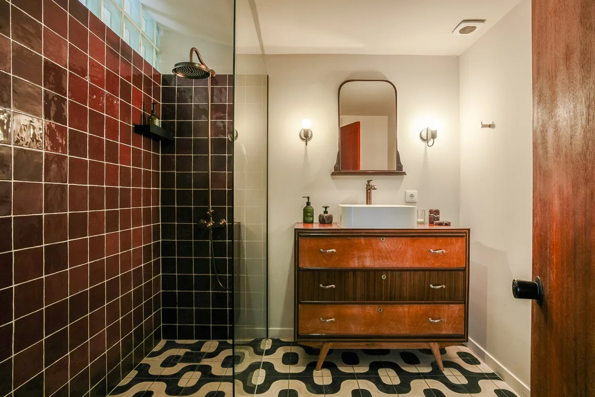 The walk-in shower in oxblood tile and brass
