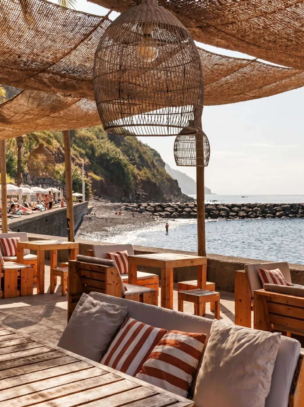 Tables at a beach bar by the sand, the Atlantic and a headland beyond