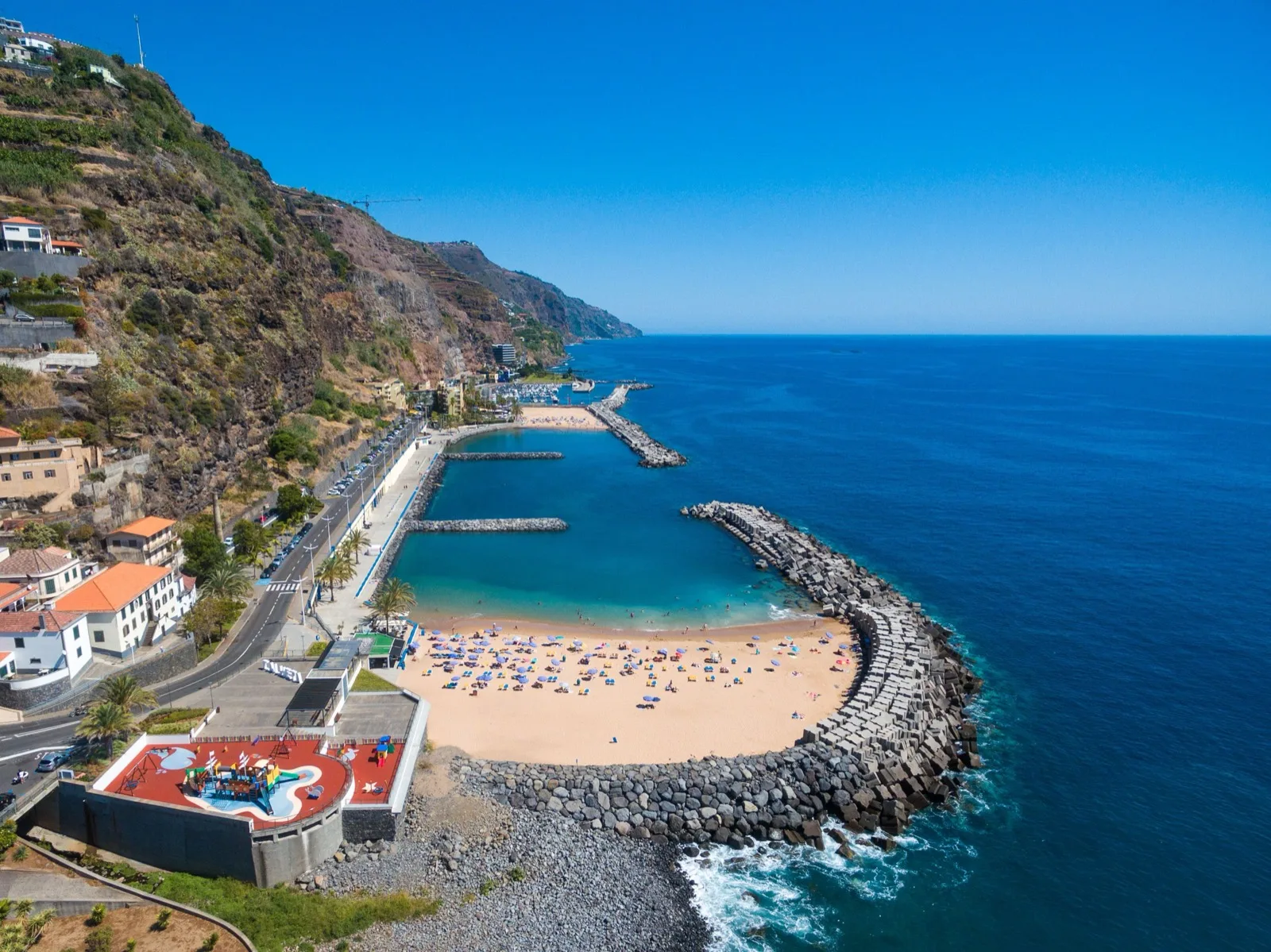 Praia da Calheta from above — a rare white-sand beach with a playground and the village, minutes from Villa Calma